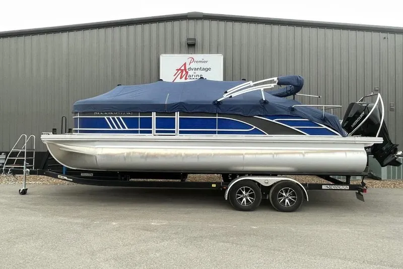 The Image of 2024 Bennington 23 LSB pontoon boat with blue cover on trailer at marina. - 0