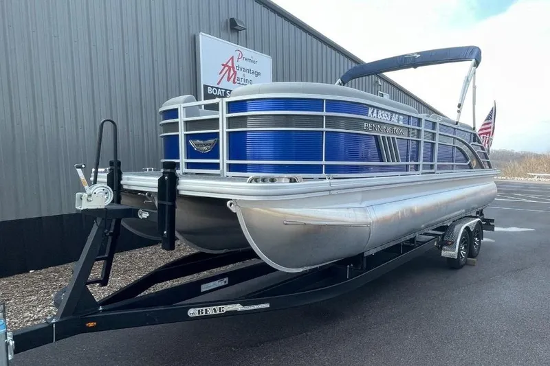Slide: The Image of 2024 Bennington 23 LSB pontoon boat on trailer, parked outside dealership. - 2
