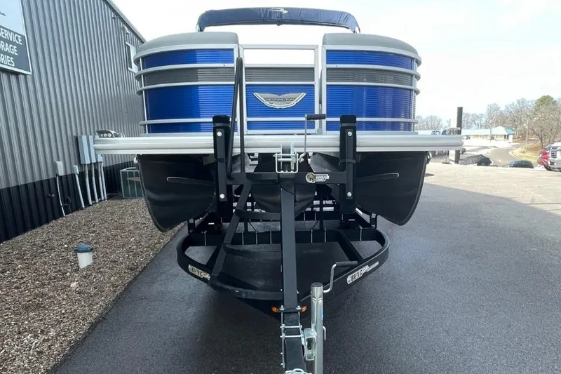 Slide: The Image of 2024 Bennington 23 LSB pontoon boat on trailer, blue exterior, parked outdoors. - 3