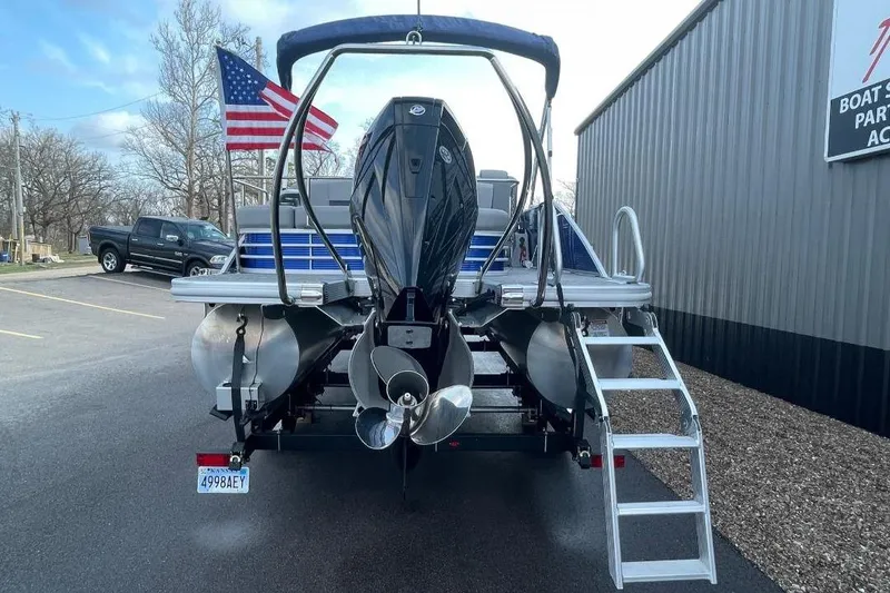 Slide: The Image of 2024 Bennington 23 LSB pontoon boat with outboard motor and American flag in parking lot. - 4