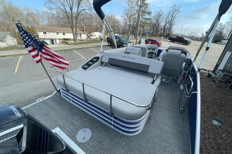 Slide: The Image of 2024 Bennington 23 LSB pontoon boat with American flag, parked in a lot. - 6
