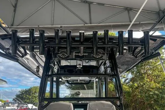 Slide: The Image of 2023 Fountain 38 Tournament Edition boat with rod holders and canopy, docked outdoors. - 23