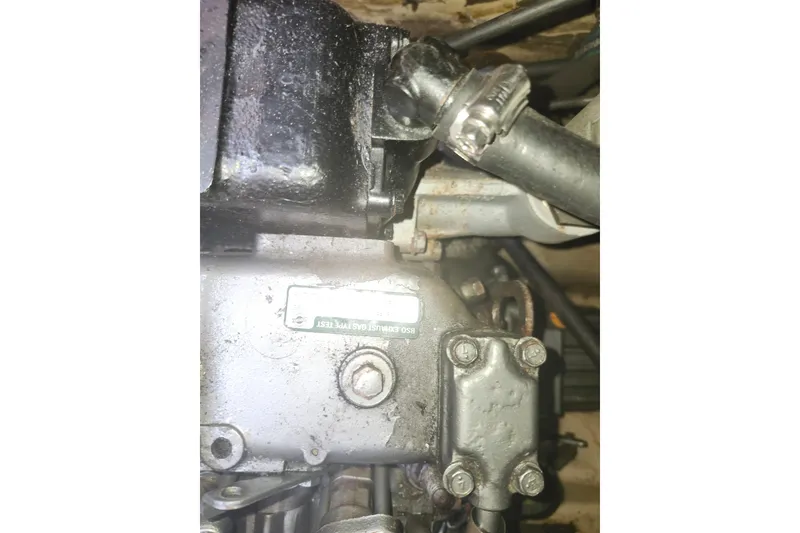 Slide: The Image of Close-up of a 1994 Island Packet 32 engine component with visible bolts and hoses. - 25