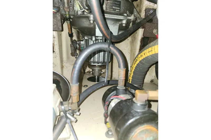 Slide: The Image of Engine compartment of a 1994 Island Packet 32 sailboat, showing hoses and mechanical components. - 26