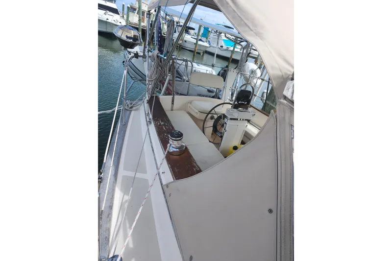 Slide: The Image of 1994 Island Packet 32 sailboat cockpit with steering wheel and seating, docked at marina. - 8