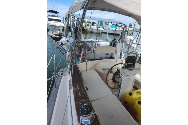 Slide: The Image of 1994 Island Packet 32 sailboat cockpit with steering wheel, docked at marina. - 9
