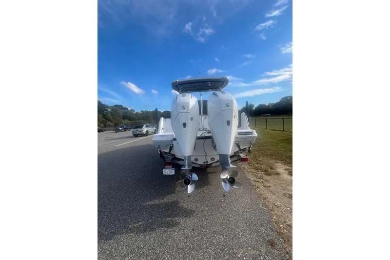 Slide: The Image of 2021 Blackfin 252 DC boat with dual outboard motors on a trailer, parked roadside. - 11