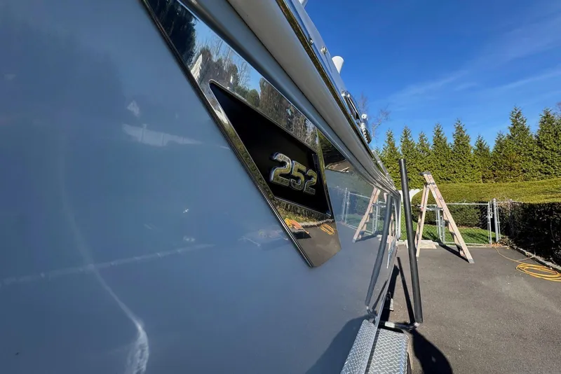Slide: The Image of 2021 Blackfin 252 DC boat side view with logo, parked outdoors under clear blue sky. - 40