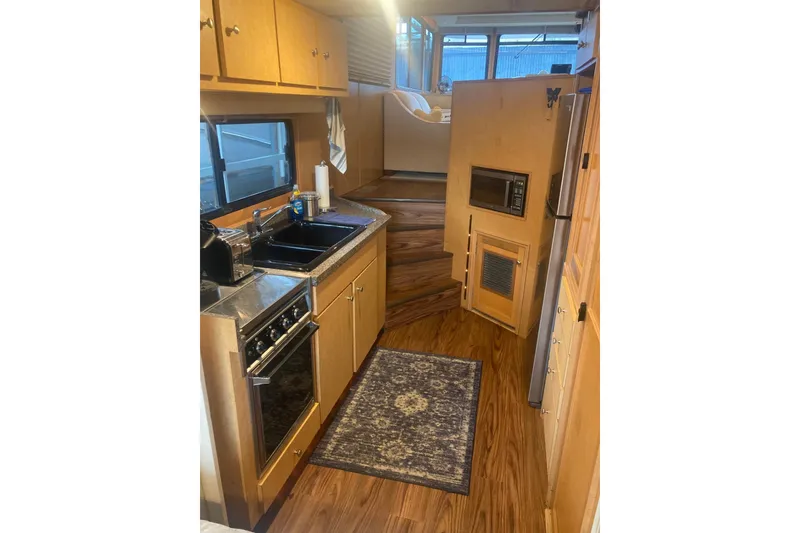 Slide: The Image of Compact kitchen in a 2006 Gibson 44 boat, featuring wood cabinetry and modern appliances. - 11