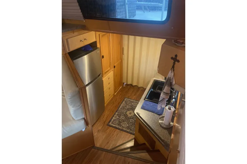 Slide: The Image of Interior of 2006 Gibson 44 boat with kitchen, fridge, and wooden cabinetry. - 16