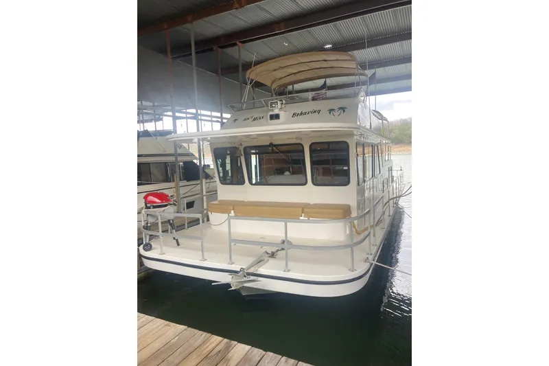 Slide: The Image of 2006 Gibson 44 houseboat docked in a covered marina, rear view. - 4