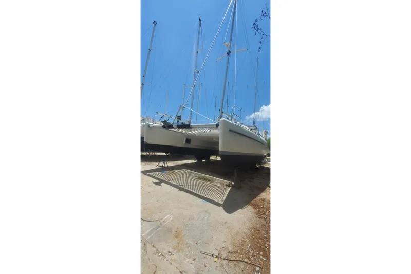 Slide: The Image of Fountaine Pajot Ninou 1992 catamaran on dry dock under clear blue sky. - 10