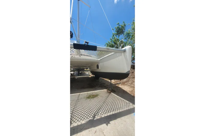 Slide: The Image of Fountaine Pajot Ninou 1992 catamaran on land, showcasing hull and netting under blue sky. - 11