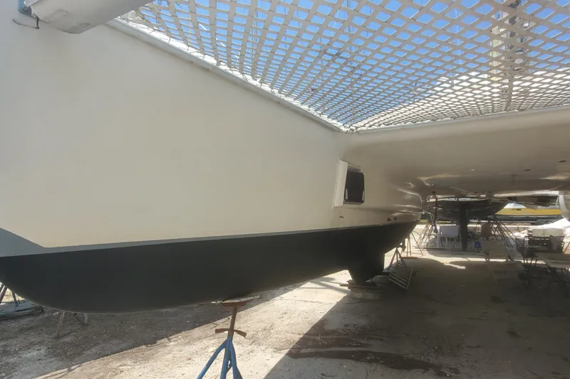 Slide: The Image of 1992 Fountaine Pajot Ninou catamaran under maintenance, showcasing hull and netting. - 6