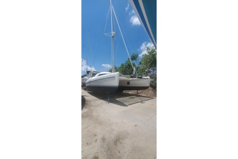 Slide: The Image of 1992 Fountaine Pajot Ninou catamaran on land, clear sky background. - 9