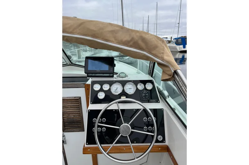 Slide: The Image of 1986 Medeiros Limestone 20 Cuddy Cabin helm with gauges and steering wheel at marina. - 2