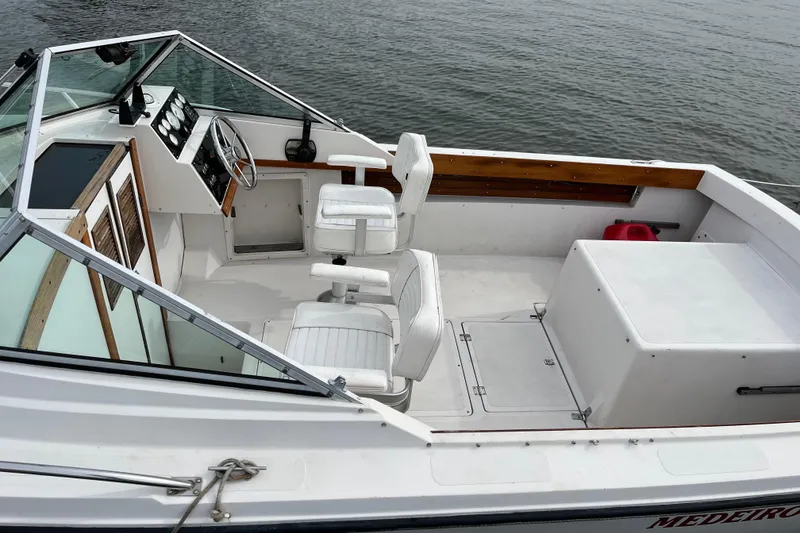 Slide: The Image of 1986 Medeiros Limestone 20 Cuddy Cabin boat interior with white seating and steering wheel. - 3