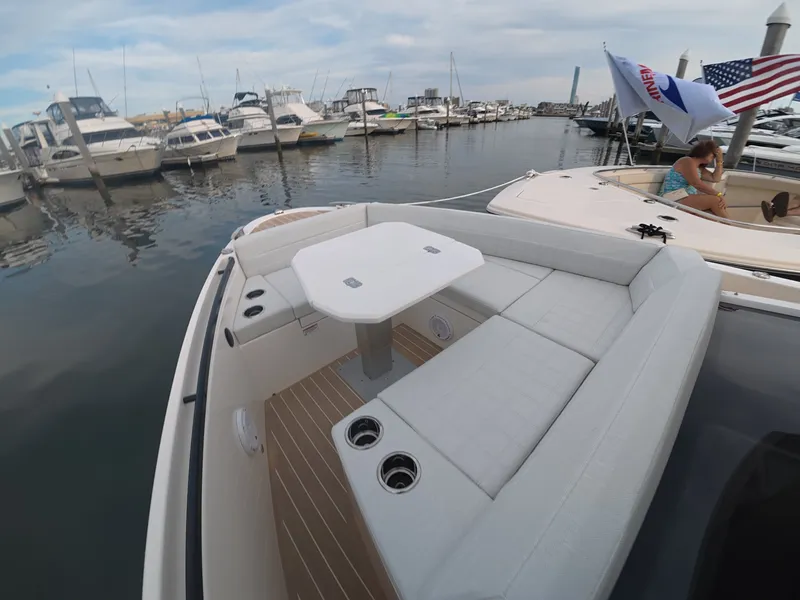 Slide: The Image of A modern boat with white cushioned seating and table in the foreground, set in a busy marina. - 21