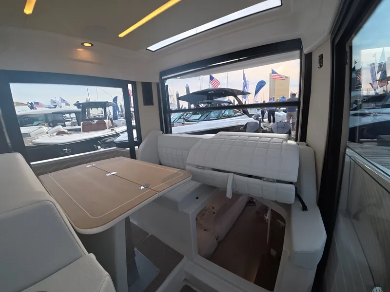 Slide: The Image of Interior view of a modern boat with white seating and a wooden table, surrounded by other boats. - 11