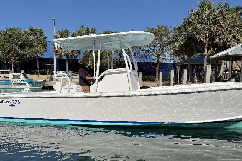 Slide: The Image of 2026 Albury Brothers 27 boat on water, with palm trees in the background. - 2