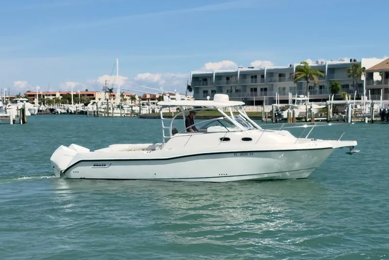 Slide: The Image of 2007 Boston Whaler 305 Conquest boat cruising in a marina with waterfront buildings. - 18