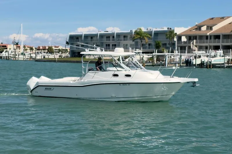 Slide: The Image of 2007 Boston Whaler 305 Conquest boat cruising near marina with waterfront buildings. - 19