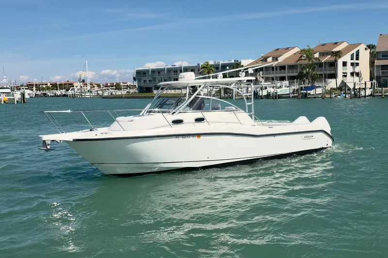Slide: The Image of 2007 Boston Whaler 305 Conquest boat cruising in a marina with waterfront buildings. - 24