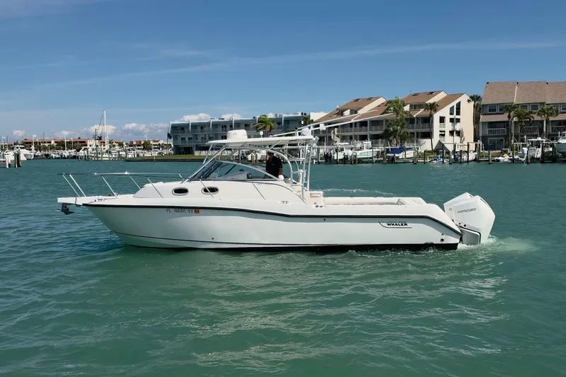 Slide: The Image of 2007 Boston Whaler 305 Conquest boat cruising in a marina with waterfront buildings. - 26