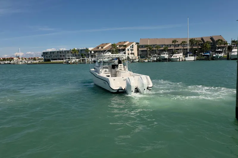 Slide: The Image of 2007 Boston Whaler 305 Conquest boat cruising in a marina with waterfront buildings. - 27