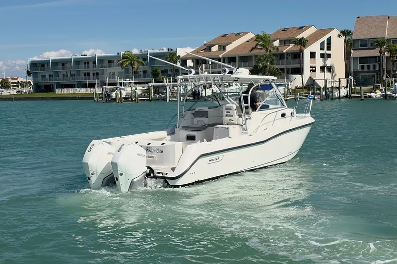 Slide: The Image of 2007 Boston Whaler 305 Conquest boat cruising in a marina with waterfront buildings. - 28
