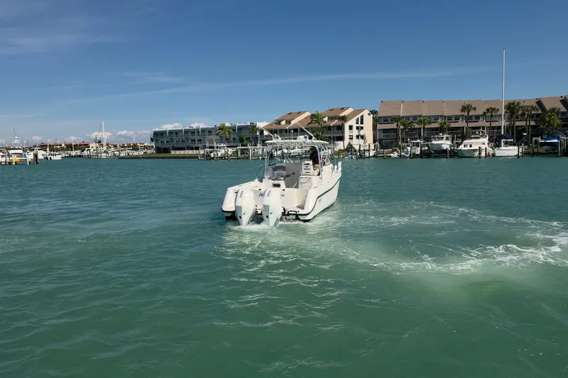 Slide: The Image of 2007 Boston Whaler 305 Conquest boat cruising in a marina with waterfront buildings. - 8