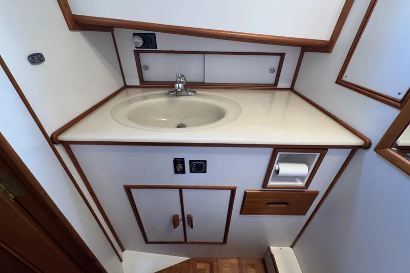 Slide: The Image of 1997 Grandbanks 36 yacht bathroom with sink, wooden trim, and storage cabinets. - 21