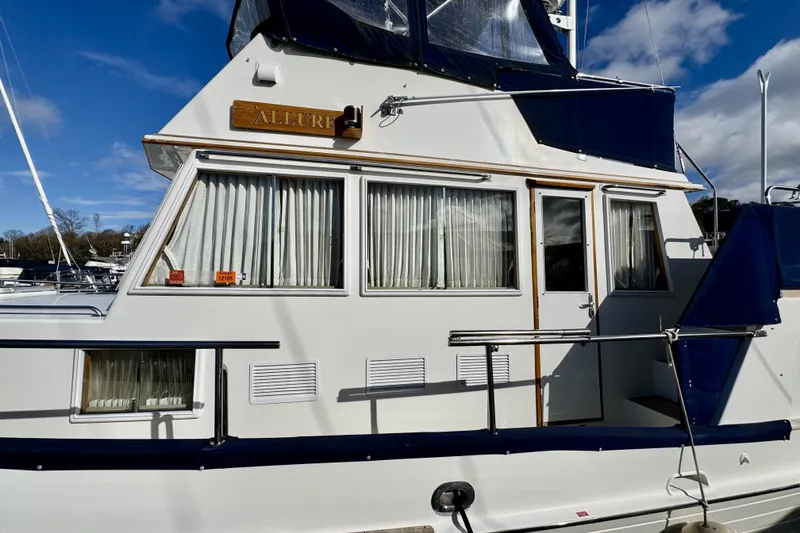 Slide: The Image of 1997 Grandbanks 36 yacht with blue accents docked under a clear sky. - 38