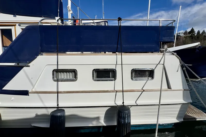 Slide: The Image of 1997 Grandbanks 36 boat side view with blue canopy and docked fenders. - 39