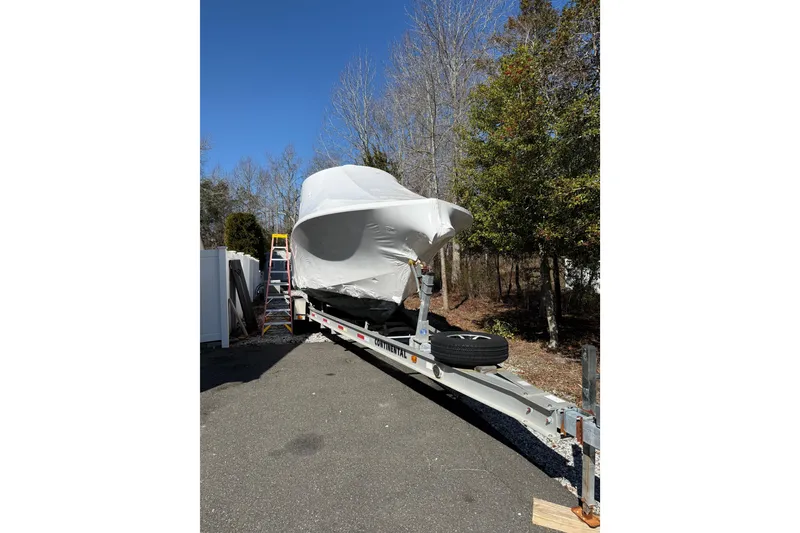 Slide: The Image of 2015 Regulator 28 Forward Seating boat covered on trailer, parked outdoors. - 10