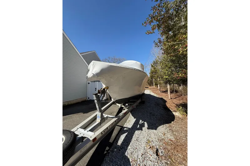 Slide: The Image of 2015 Regulator 28 Forward Seating boat covered on trailer, parked beside house. - 11