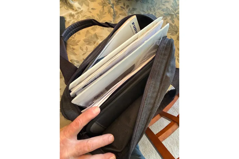 Slide: The Image of Bag with documents, including Regulator 28 Forward Seating 2015 manual, on a floral tablecloth. - 16