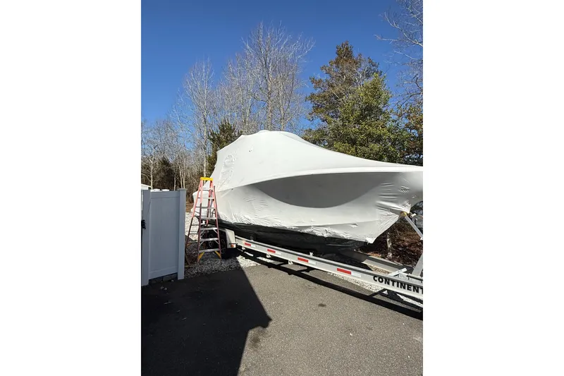 Slide: The Image of 2015 Regulator 28 Forward Seating boat covered on trailer, surrounded by trees. - 9