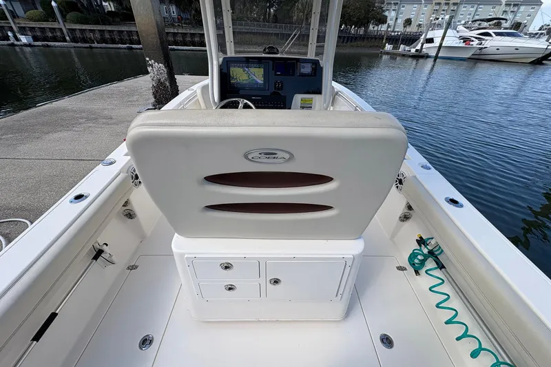 Slide: The Image of 2020 Cobia 240 Center Console boat interior with helm and seating, docked by the water. - 13