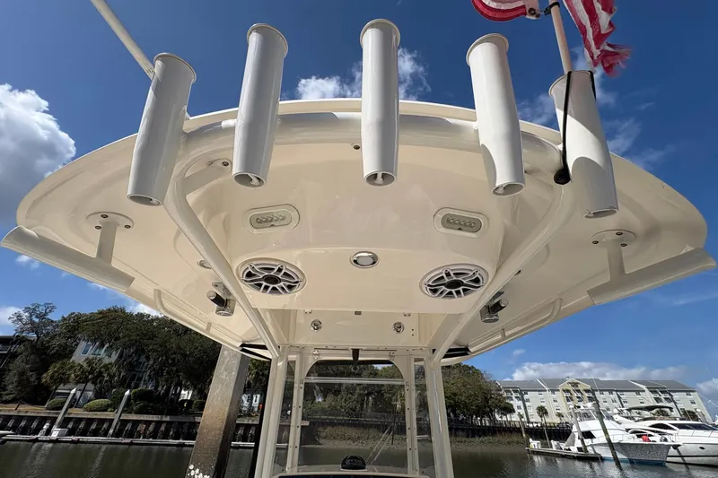Slide: The Image of 2020 Cobia 240 Center Console boat with rod holders and speakers, docked under blue sky. - 16