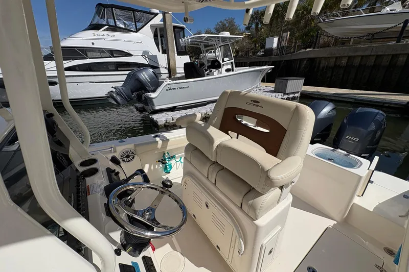 Slide: The Image of 2020 Cobia 240 Center Console boat interior with steering wheel and seating at marina. - 19