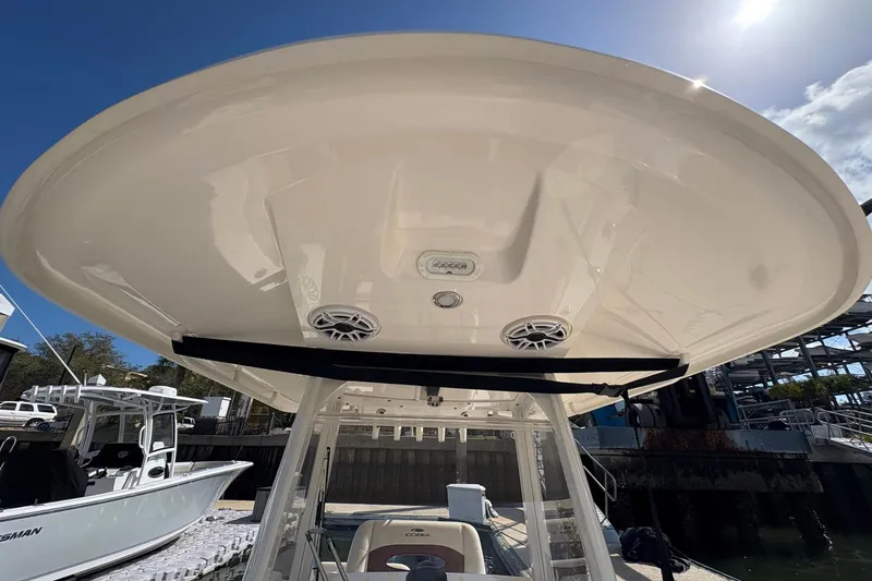 Slide: The Image of 2020 Cobia 240 Center Console boat with T-top and speakers, docked under sunny sky. - 27
