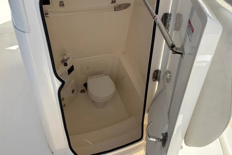 Slide: The Image of 2020 Cobia 240 Center Console boat interior with compact marine toilet. - 30
