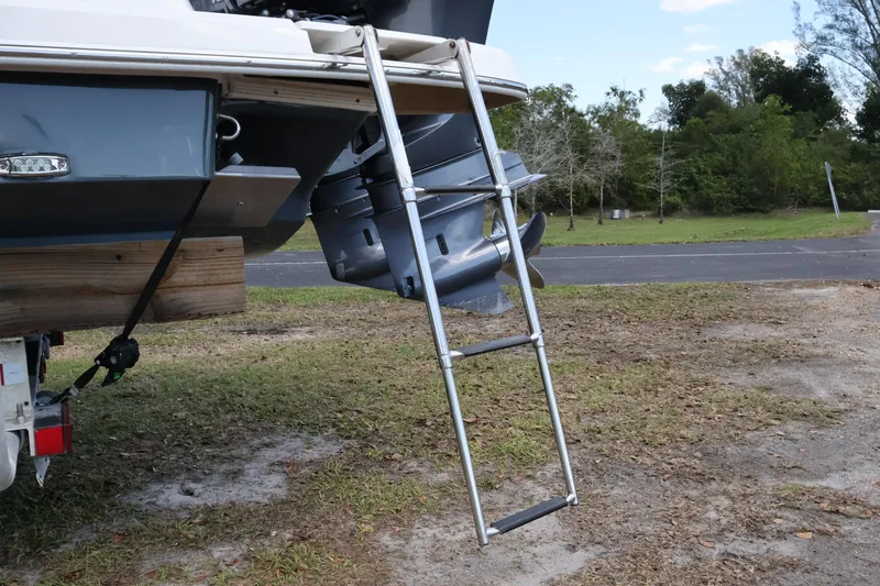 Slide: The Image of 2019 Regal 29 OBX boat with ladder and outboard motor on grassy area. - 14