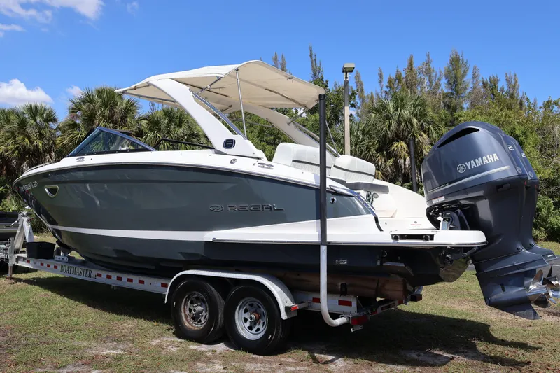 Slide: The Image of 2019 Regal 29 OBX boat on trailer with Yamaha outboard motor, surrounded by trees. - 2