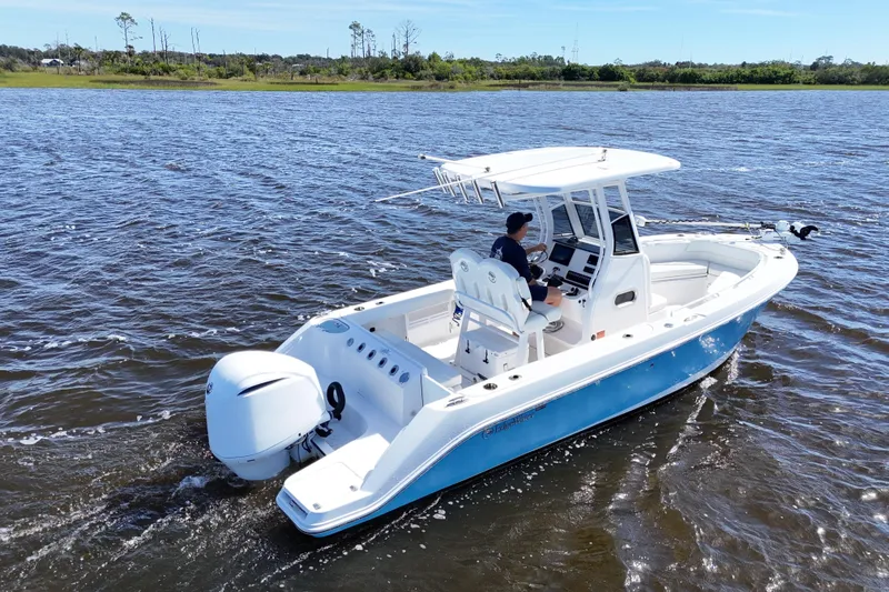Slide: The Image of 2019 Edgewater 230CC boat cruising on a calm lake with a person at the helm. - 12