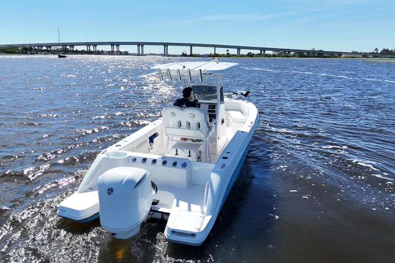 Slide: The Image of 2019 Edgewater 230CC boat cruising on a sunny day near a bridge. - 14