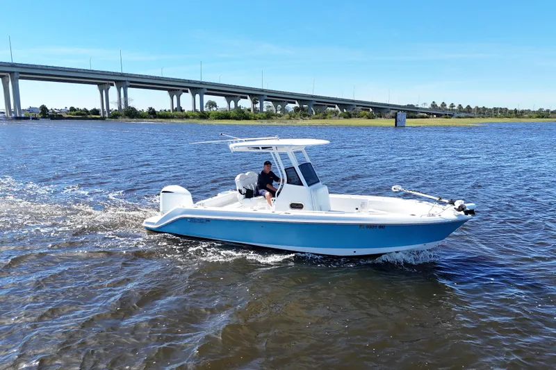 Slide: The Image of 2019 Edgewater 230CC boat cruising on a sunny day near a bridge. - 16