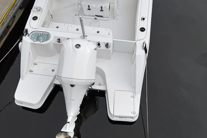 Slide: The Image of 2019 Edgewater 230CC boat with outboard motor, docked on calm water. - 25