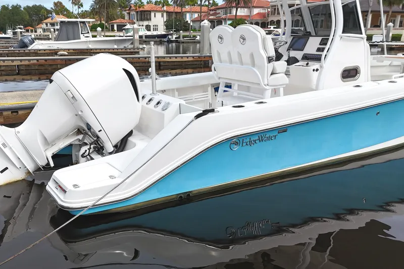 Slide: The Image of 2019 Edgewater 230CC boat docked, featuring a sleek design and powerful outboard motor. - 26